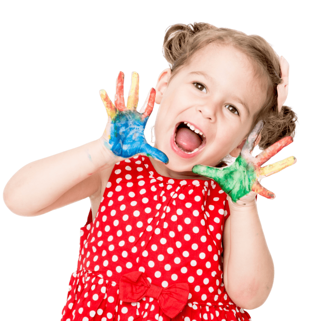 A young girl in a red polka dot dress shows her colorful paint-covered hands, smiling with an open mouth.